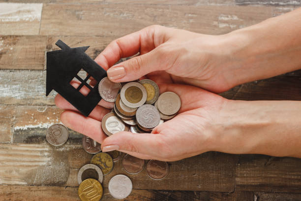 istock Gold, silver coins and decorative house in the hands 1279340218