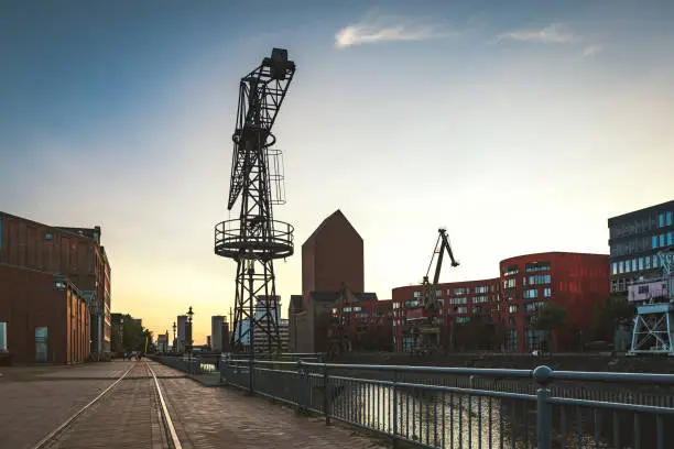 low angle view on old crane and  buildings at the canal side of inner harbor in Duisburg at late summer evening