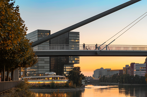 silhouettes of cyclists and pedestrians in the sunset light on bridge over Rhine river in Düsseldorf