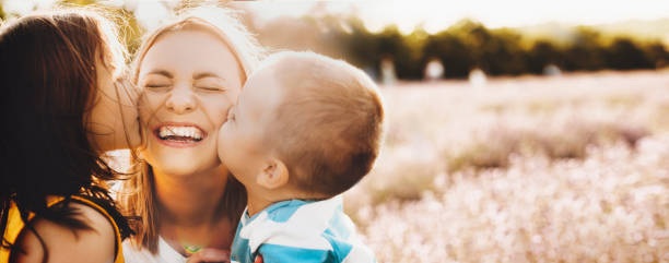 kaukaska matka pocałowana przez swoje dzieci pozujące w lawendowym polu uśmiecha się w słoneczny letni dzień - single mother one parent child kissing zdjęcia i obrazy z banku zdjęć