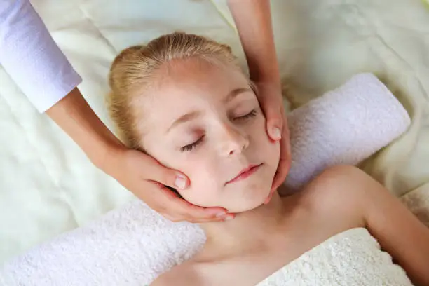 Masseur doing face massage to child.