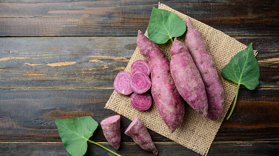Raw purple sweet potatoes on wooden background, Organic vegetables
