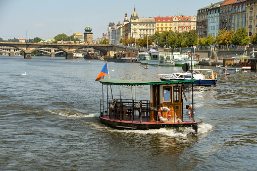 Prague, Czech Republic - July 2018: Small water taxi crossing the River Vltava, which runs through the centre of Prague