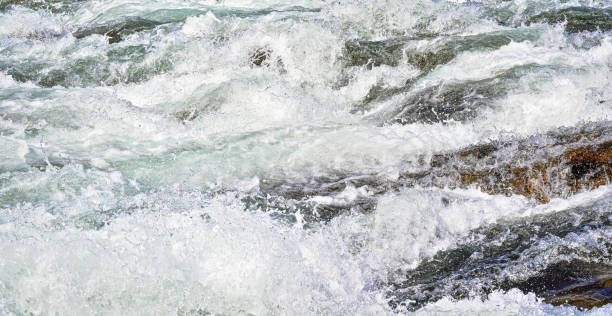 istock Rapid spring river flowing over rocks on sunny day, forming white water waves, closeup detail - abstract nature background 1279350955