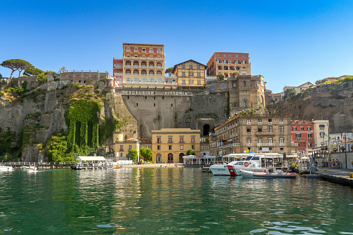 Sorrento, Italy - August 2019:  High cliffs of the town of Sorrento. On top of the cliff above the harbour is the luxury hotel, the Excelsior Grand Vittoria, which is owned by Albergo Hotels.