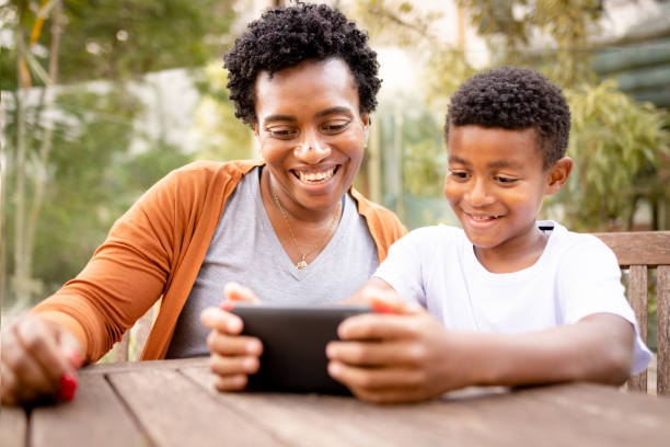 istock Mother and son using cell phone outdoors and smiling 1279354234