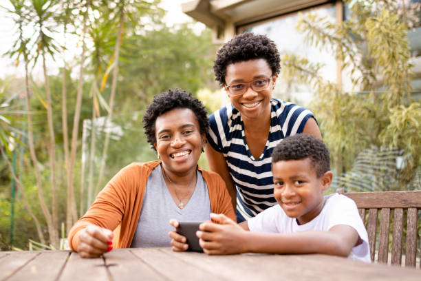 istock Two women and a boy using cell phone and looking at camera 1279354244