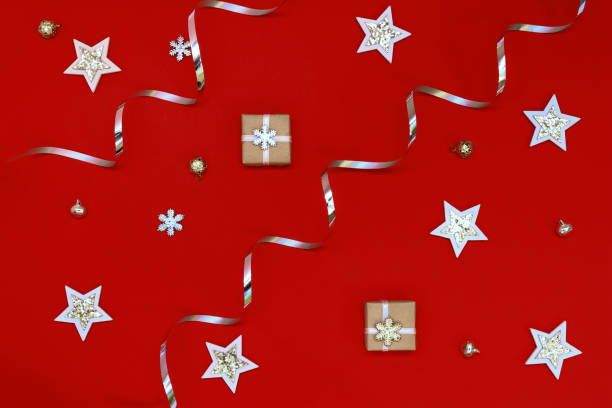 Flat composition of Christmas decorations in silver and holiday boxes on a red background.