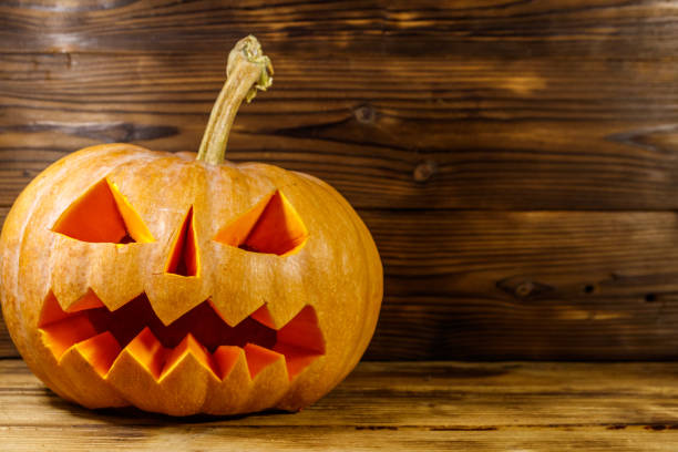 istock Spooky Halloween pumpkin jack-o-lantern on a wooden background 1279356852