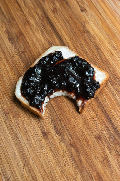istock Blackberries jam spread on a piece of white bread big bite size missing top view 1279359772
