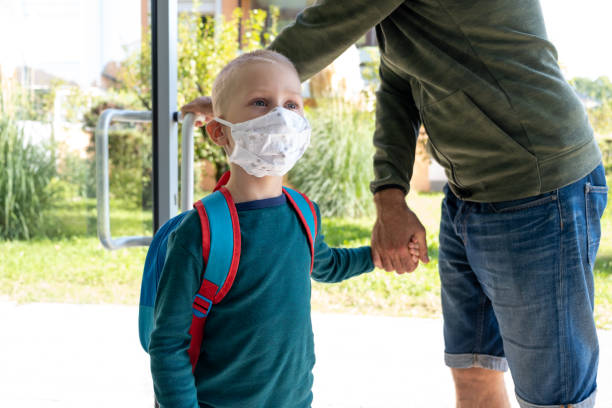 istock Father bringing his son with protective mask to school / kindergarten and holding his hand 1279359985