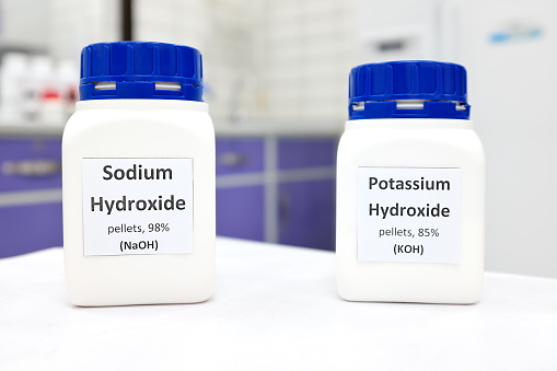 Selective focus of a bottle of pure sodium hydroxide and potassium hydroxide chemical compound. Chemistry research laboratory background with copy space.