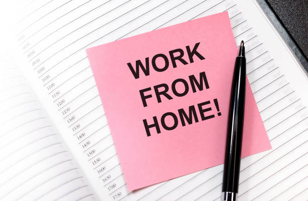 istock work from home, pink stickers, black pen, notebook with pink sticker at the wooden table background 1279361921