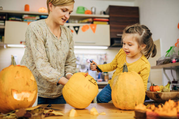 istock Simple family having fun while carving pumpkins for Halloween decoration in their kitchen 1279363646