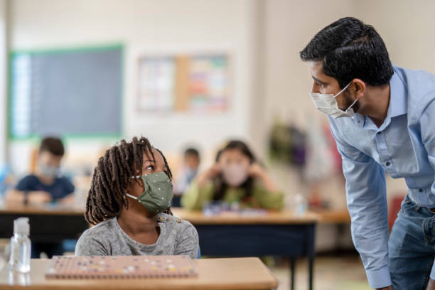 istock Female elementary school student sitting at her desk wearing a mask 1279364058
