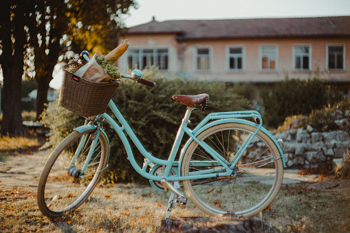 Vintage style bike with a wicker basket containing flowers, bread. Shallow DOF.