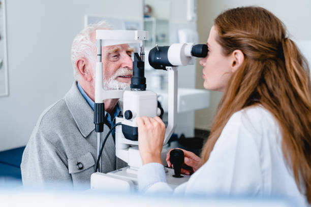 médico oftalmológico femenino que diagnostica la vista del paciente de edad avanzada con equipo oftálmico - looking eyesight optometrist focus fotografías e imágenes de stock