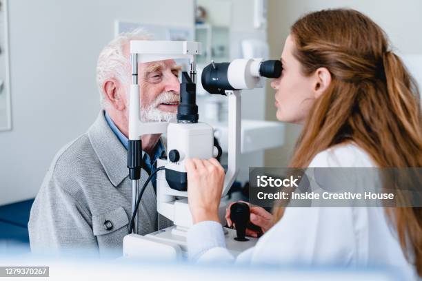 Female Ophthalmic Doctor Diagnosing Elderly Patients Sight Using Ophthalmic Equipment Stock Photo - Download Image Now