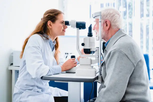 Photo of Female ophthalmologist examining mature man`s eyes