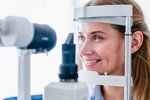 photo de plan rapproché d’un patient de jeune femme de sourire pendant l’examen ophtalmique de vue - examen ophtalmologique photos et images de collection