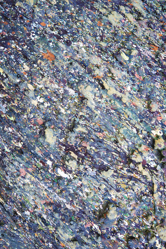 Grunge texture of stone surface stained with motley paint spots.
