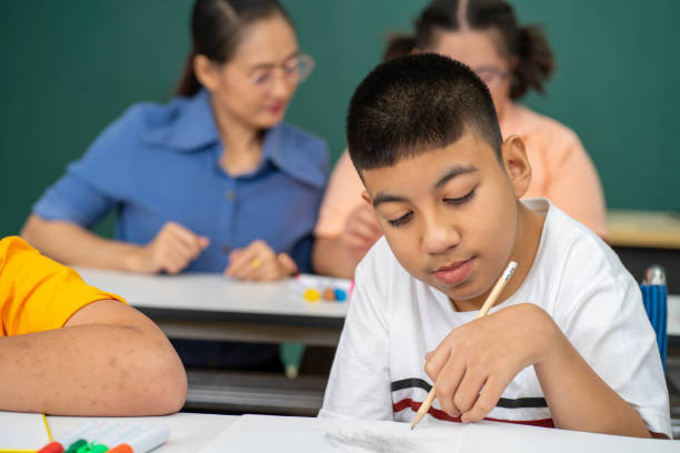 istock disability kid with autism boy in special classroom studying with Asian teacher 1279372572