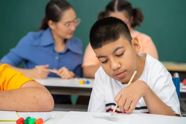 disability kid with autism boy in special classroom studying with Asian teacher