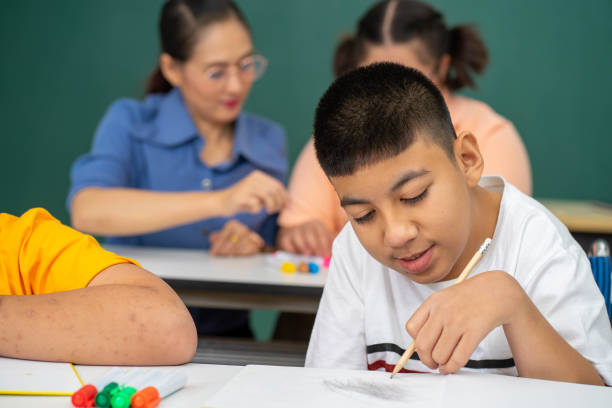 istock disability kid with autism boy in special classroom studying with Asian teacher 1279372578