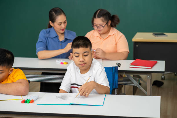 istock disability kid with autism boy in special classroom studying with Asian teacher 1279372591