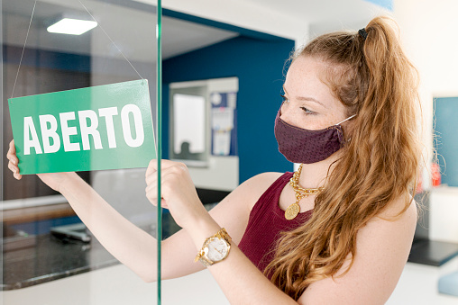 Young woman wearing protective mask opening company