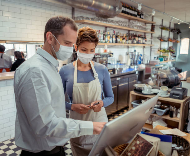 istock Waitress and manager at a restaurant working together wearing facemasks 1279375794