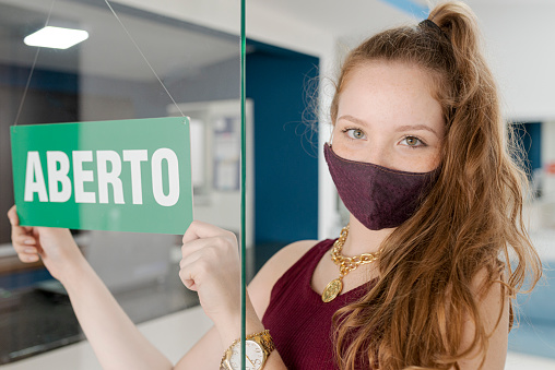 Portrait of businesswoman wearing protective mask opening her business.
