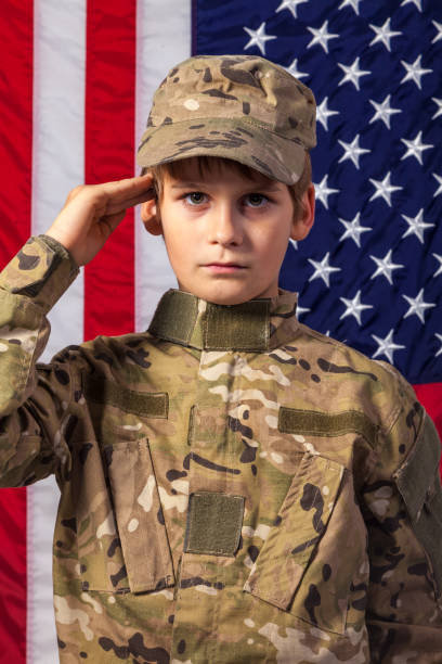 アメリカ国旗を持つ兵士のような服を着た少年 - child military saluting flag ストックフォトと画像