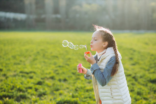 istock Child plays with soap bubbles on the green grass. 1279384079