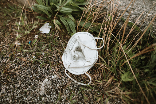 A used protective face mask lying on the floor outdoors