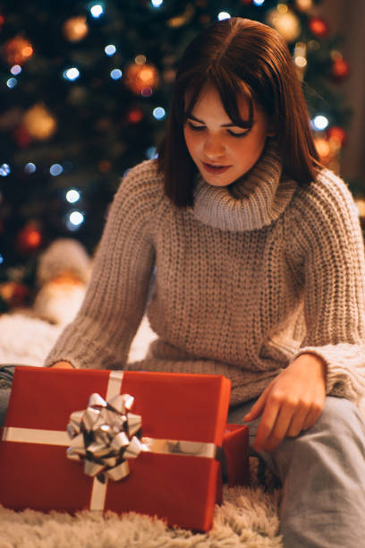 istock Happy Girl with a Smile Peeks Inside a Christmas Gift Box with Light 1279387499