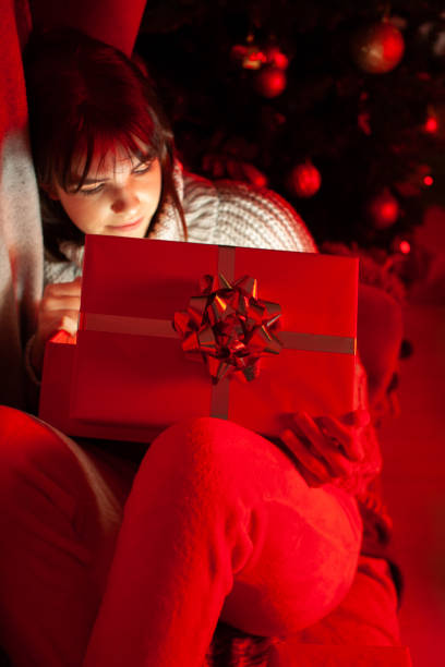 istock Happy Girl with a Smile Peeks Inside a Christmas Gift Box with Light 1279387683
