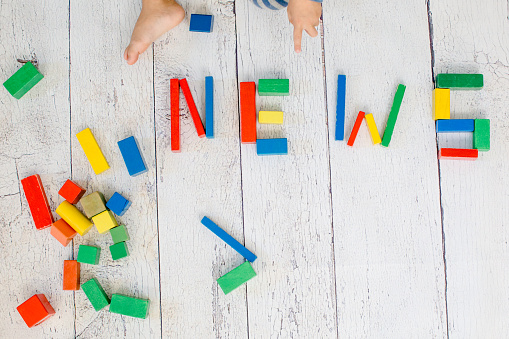 NEWS formed by multi colored toy bricks. message written in wooden blocks. Child shows with his fingers