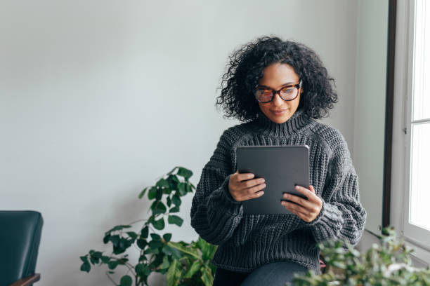 trabajar desde casa: una mujer joven que hace una tableta digital para leer/ver algo - tableta digital fotografías e imágenes de stock