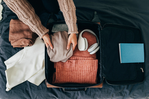 Manos de una mujer anónima que empaca su maleta para las vacaciones de invierno, una vista aérea photo