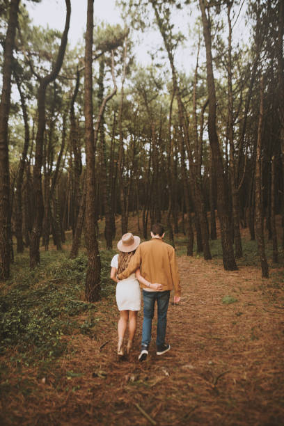 Rear view of a young couple walking in a forest in autumn