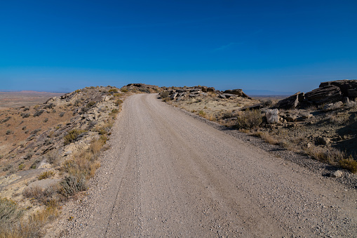 Dirt road through Wyoming's colorful badlands at the McCullough peaks wild horse refuge. Colorful badlands and desert mountains with rolling foothills and steep slopes, cliffs and canyons.