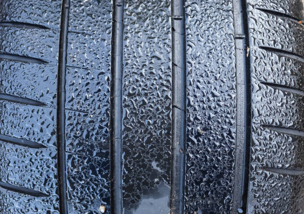 istock Black big tires in a close up view with water drops. Tire tread problems. 1279403590
