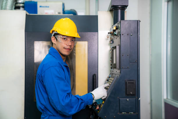 Mechanical technician operative entering data in cnc milling cutting machine at factory at tool workshop in metal machining industry.