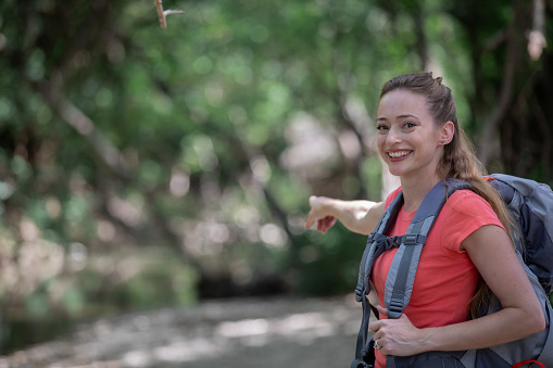 Woman who is hiking smiles while pointing ahead