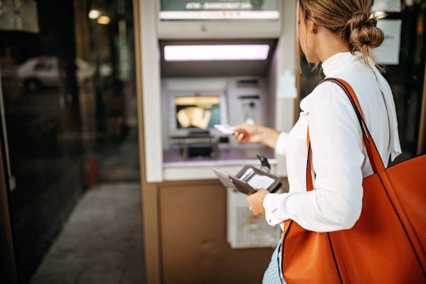 istock Women using ATM machine to withdraw money 1279421277