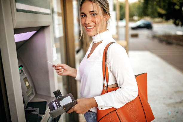 istock Women using ATM machine to withdraw money 1279421904