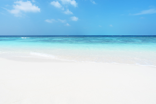 Sunny white beach with clear turquoise sea and blue sky background