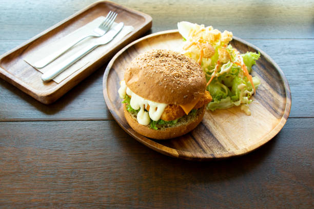 istock Fried fish fillet burger with vegetable salad on wood plate background 1279423836