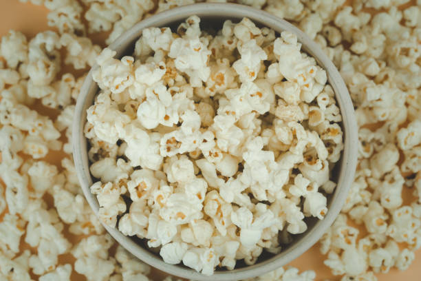 Top view of a pile of popcorn in bowl and scattered on table